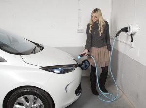 lady charging Renault Zoe in garage on white wall mounted homecharge unit