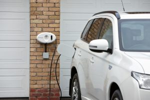 Chargemaster tethered white homecharge unit on garage charging Mitsubishi SUV