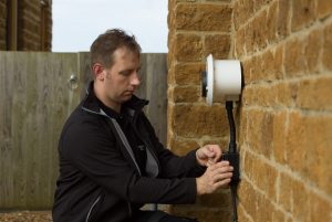 Installation of a white tethered Chargemaster homecharge unit on a wall in a driveway