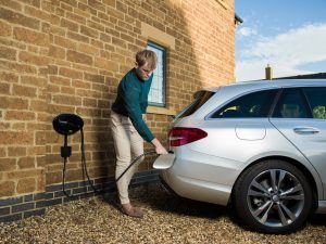 Home charging a silver EV vehicle using a black wall mounted homecharge unit
